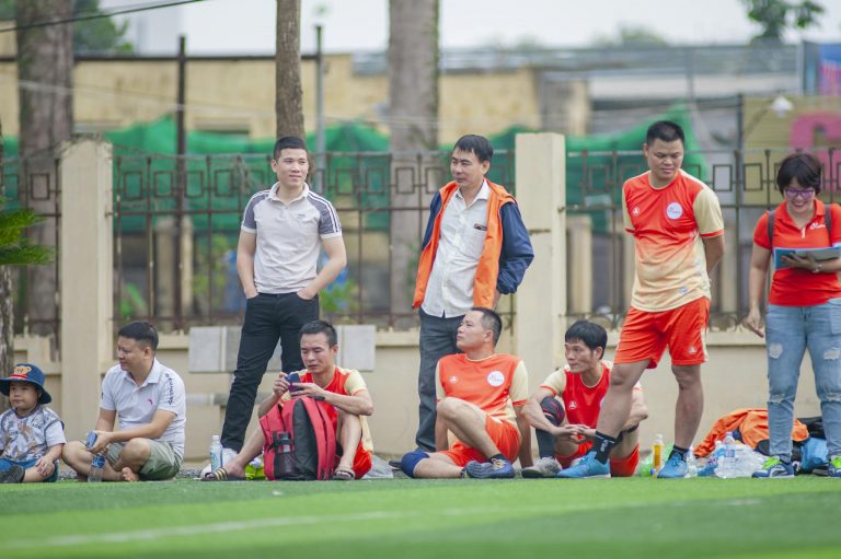 Amateur football team resting during a match in Hà Nội, Vietnam. Vibrant community scene.