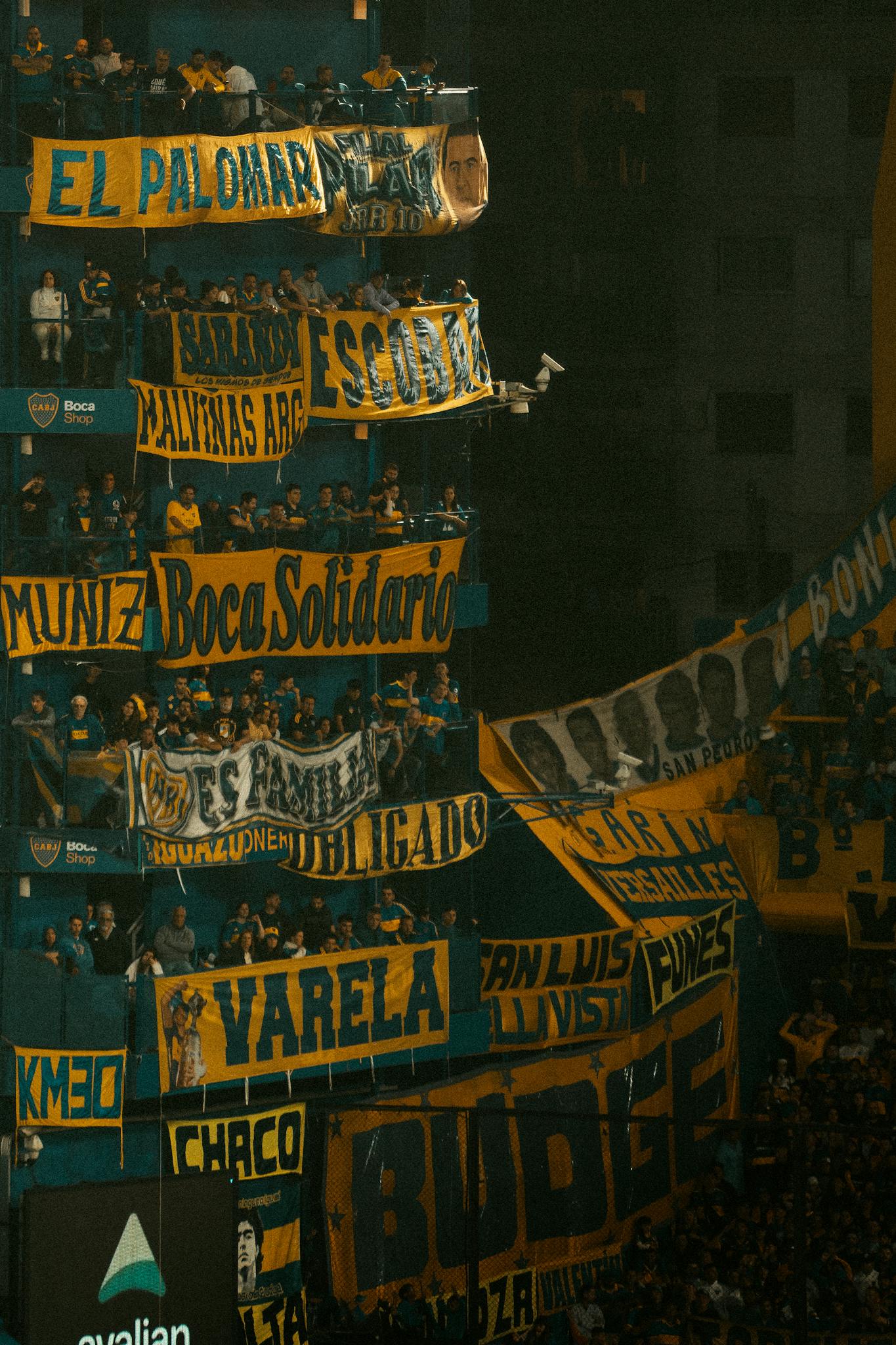 Energetic crowd of Boca Juniors fans showcasing vibrant banners at La Bombonera stadium, Buenos Aires.